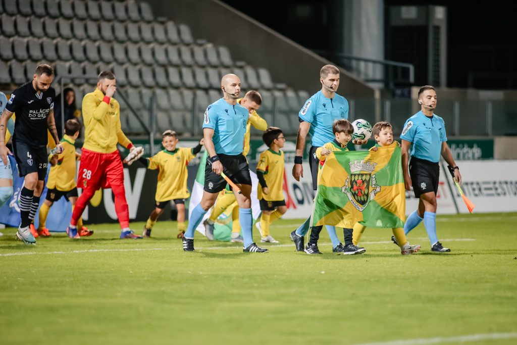 Crianças a entrar no Estádio Capital do Móvel com a equipa de arbitragem e as equipas do FC Paços de Ferreira e do Académico de Viseu FC, levando bandeiras das freguesias do concelho de Paços de Ferreira, no dia do Município (6 de novembro).